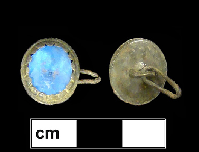 Copper alloy button setting with a bright blue ovoid faceted inset. The scalloped edge of the setting holding the inset and the oval shape are characteristics that appeared in the second half of the 18th century.